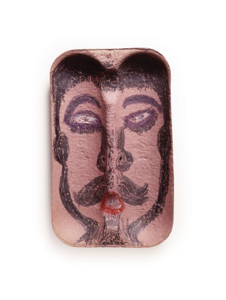 Pink, textured fruit carton with a drawing of a distorted face, outlined in black crayon, that has a thick handlebar mustache and small red mouth shaped into an O.