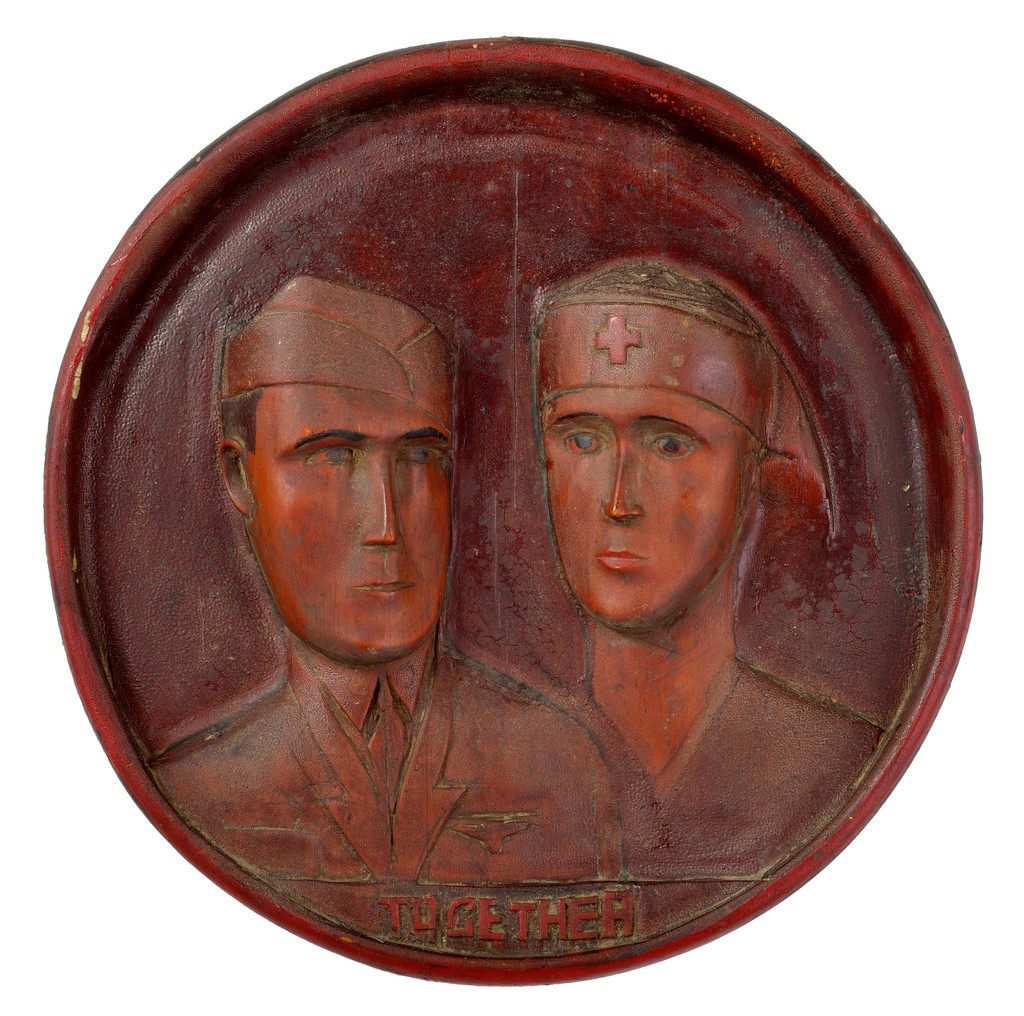 American relief carved wooden plaque depicting WWII head and shoulder portraits of doctor and nurse in uniform, inscribed Together under figures with traces of red paint