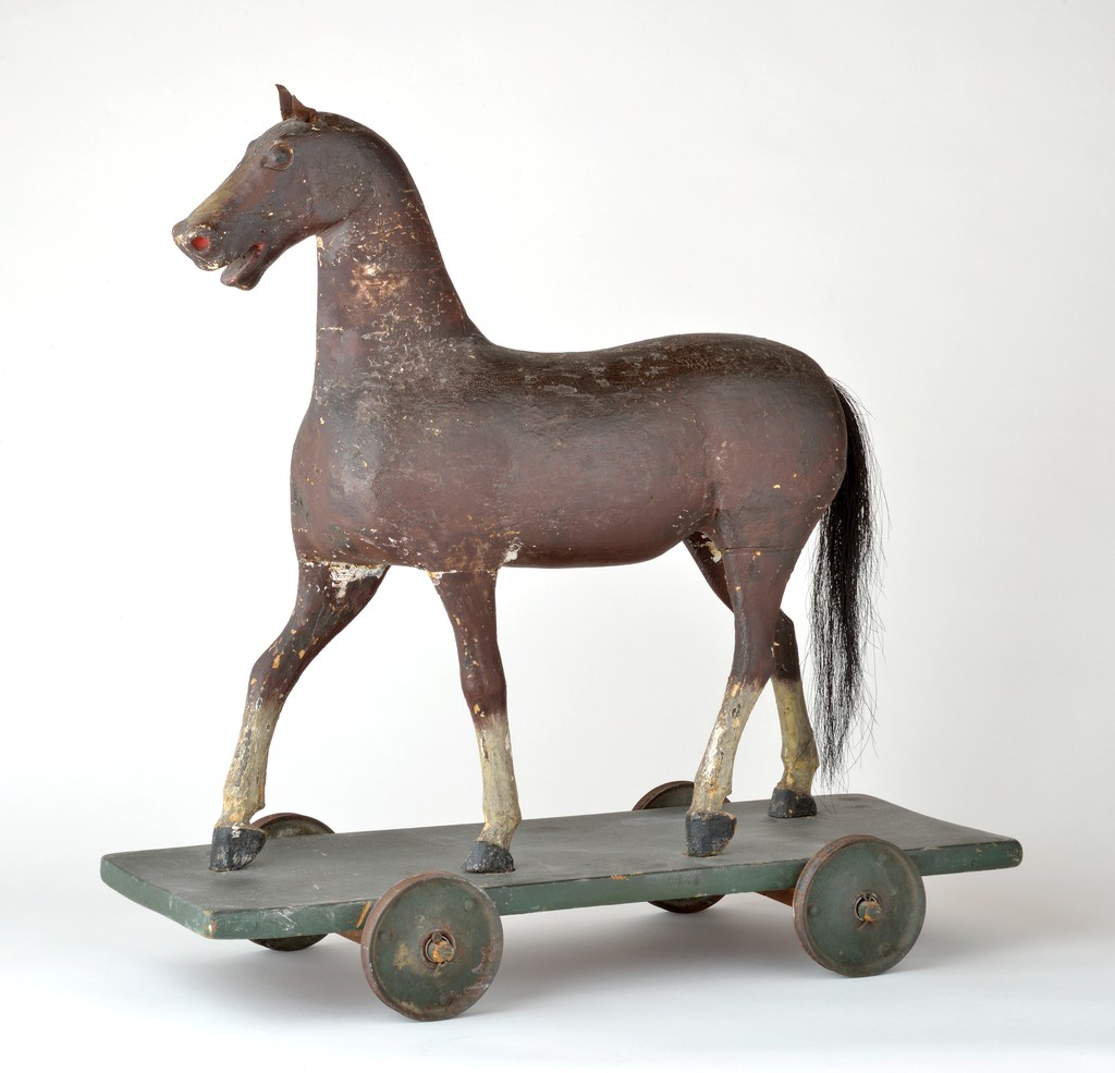American polychrome carved wooden and gesso horse pull toy on wooden base with metal wheels, leather ears, and horsehair tail