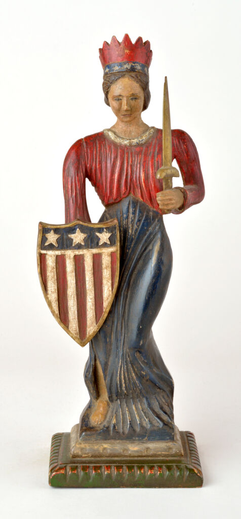 American polychrome carved wooden sculpture in the form of Lady Liberty with crown, shield and sword on carved wooden base, exhibited at the American Folk Art Museum, NYC