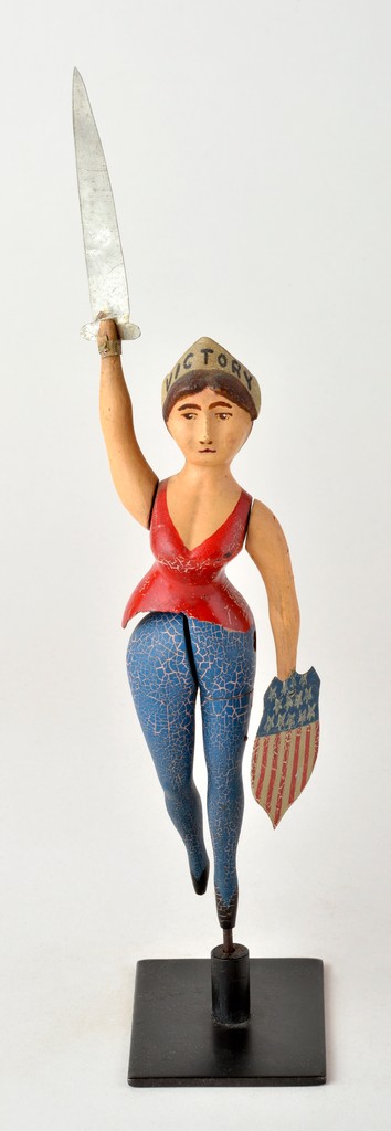 American polychrome carved wooden articulated woman, inscribed Victory on crown, metal sword and shield in hands that rotate when leg spins, on metal base