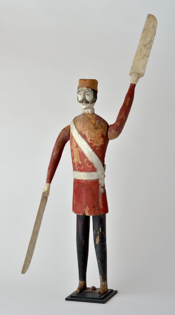 Polychrome carved wooden figural soldier whirligig in wooden base, probably English, arms restored