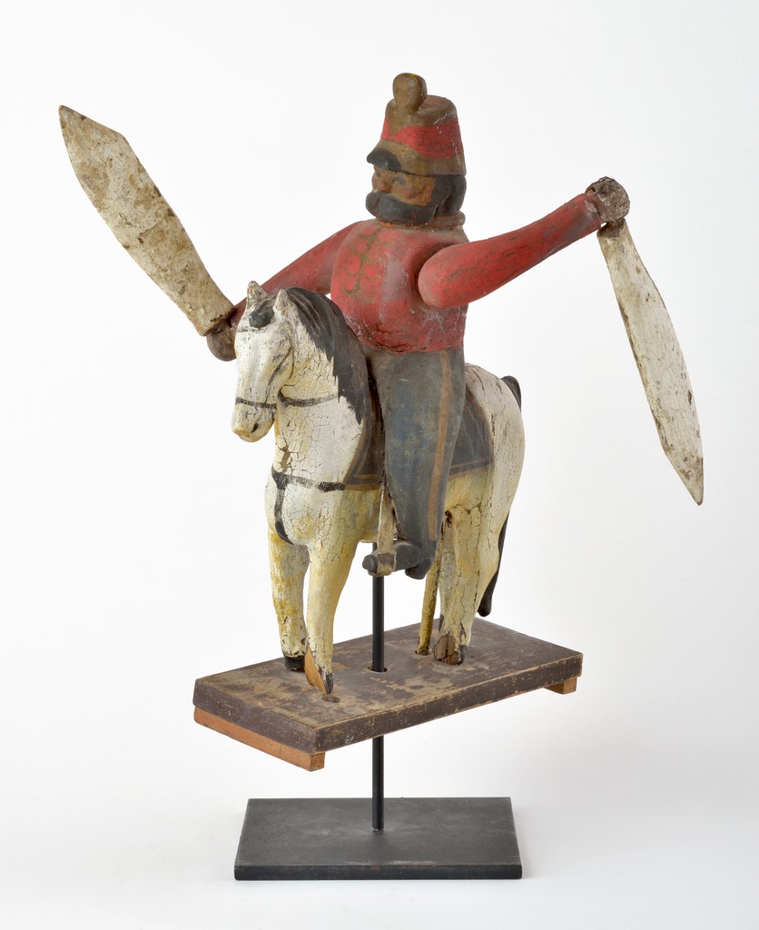 English polychrome carved wooden figural soldier on horseback whirligig on wooden base on metal stand, some damage to horse’s hooves