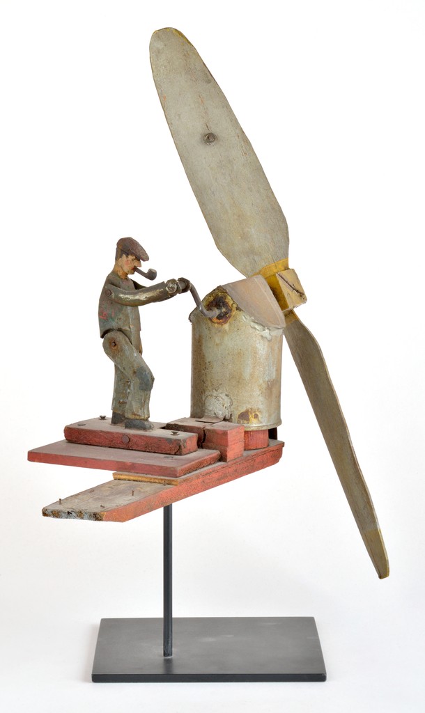 American polychrome carved wooden figural whirligig in the form of worker smoking a pipe and turning a crank to turn a blade on metal stand