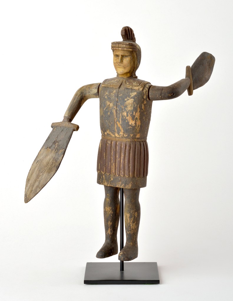 American polchrome carved wooden figural whirligig in the form of Roman soldier wearing helmet with sword and shield paddles on metal base
