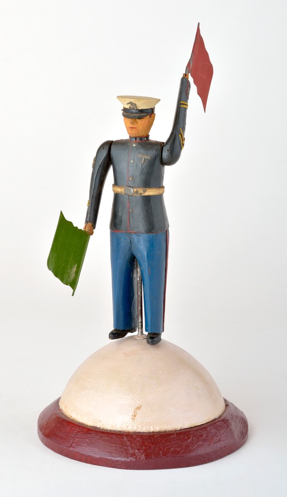 American polychrome carved wooden Marine whirligig in uniform with cap and green and red flags as blades on white domed bas with red rim