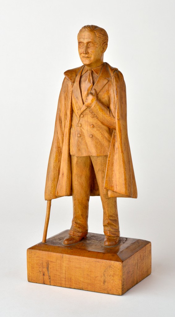 American full-figure carved wooden sculpture depicting standing Franklin Roosevelt leaning on a cane by Vestor Lowe on wooden base